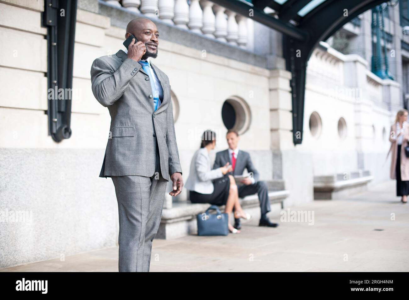 Businessman on phone at bus stop Stock Photo