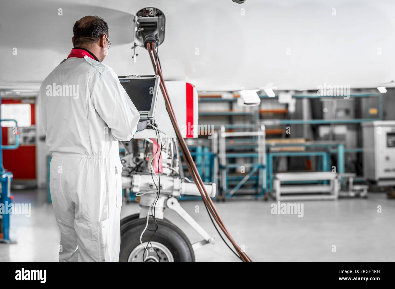 Man using laptop by airplane in hangar Stock Photo