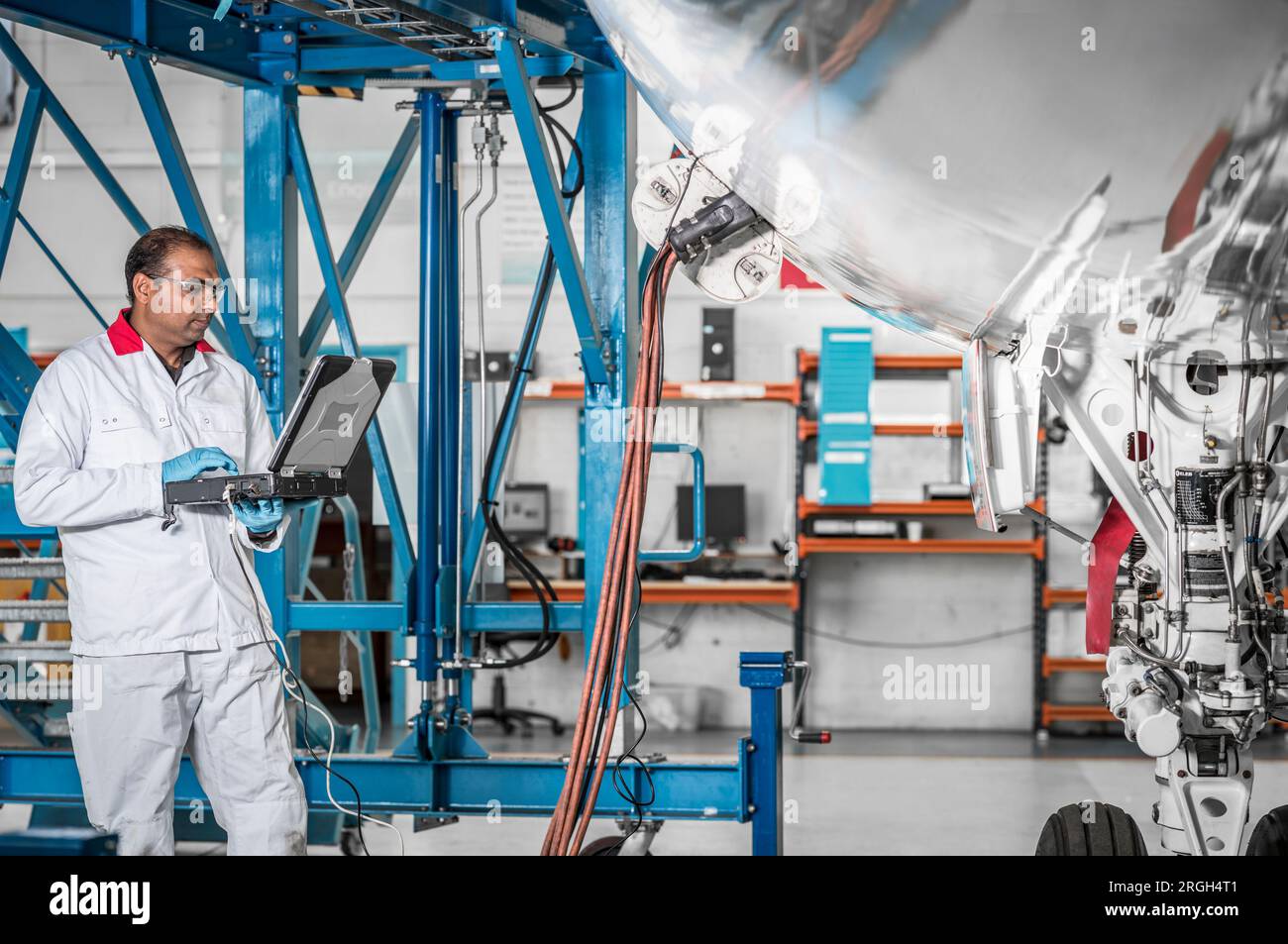Man using laptop by airplane in hangar Stock Photo