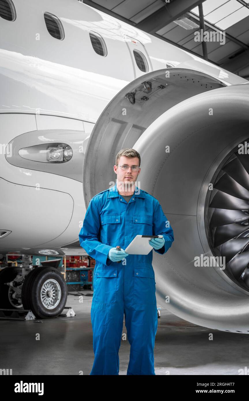 Young man holding digital tablet by airplane engine Stock Photo