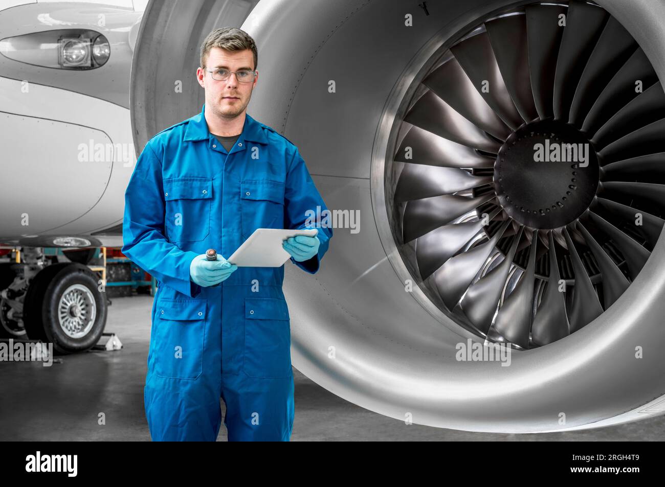 Young man holding digital tablet by airplane engine Stock Photo