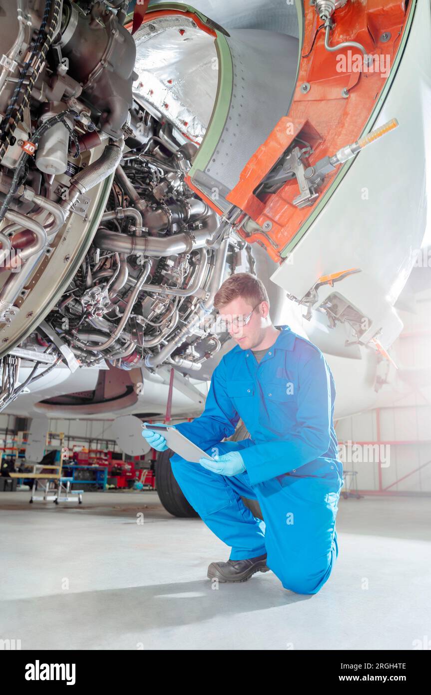 Crouched man using digital table by airplane Stock Photo
