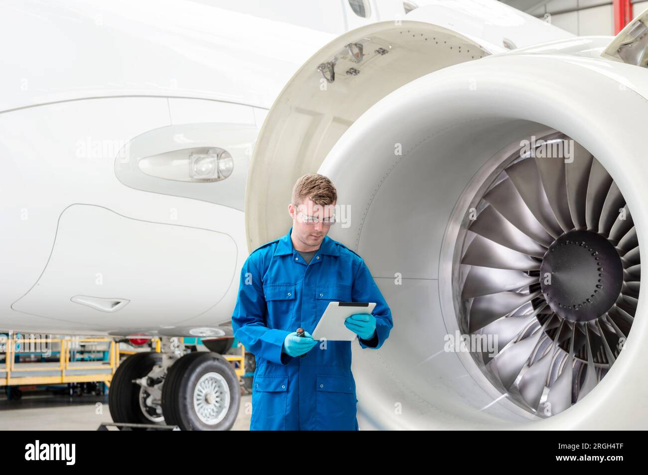 Young man using digital tablet by airplane engine Stock Photo