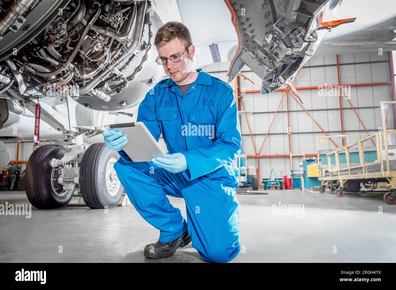 Crouched man using digital table by airplane Stock Photo