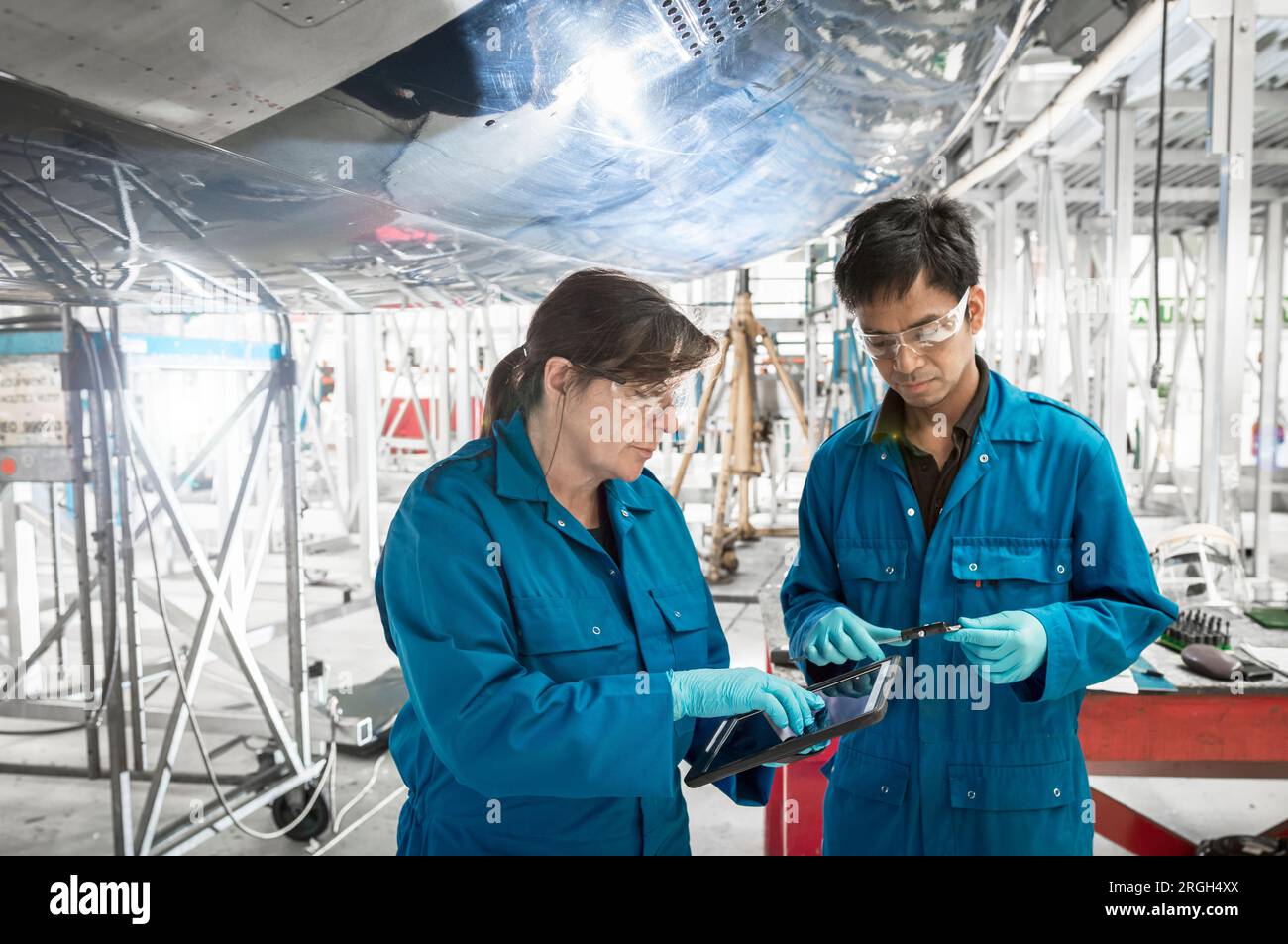 Workers using digital tablet by airplane in hangar Stock Photo