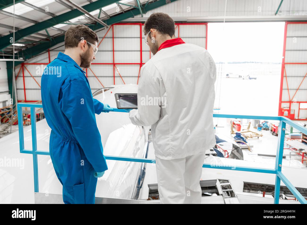 Men using digital tablet in airplane hangar Stock Photo