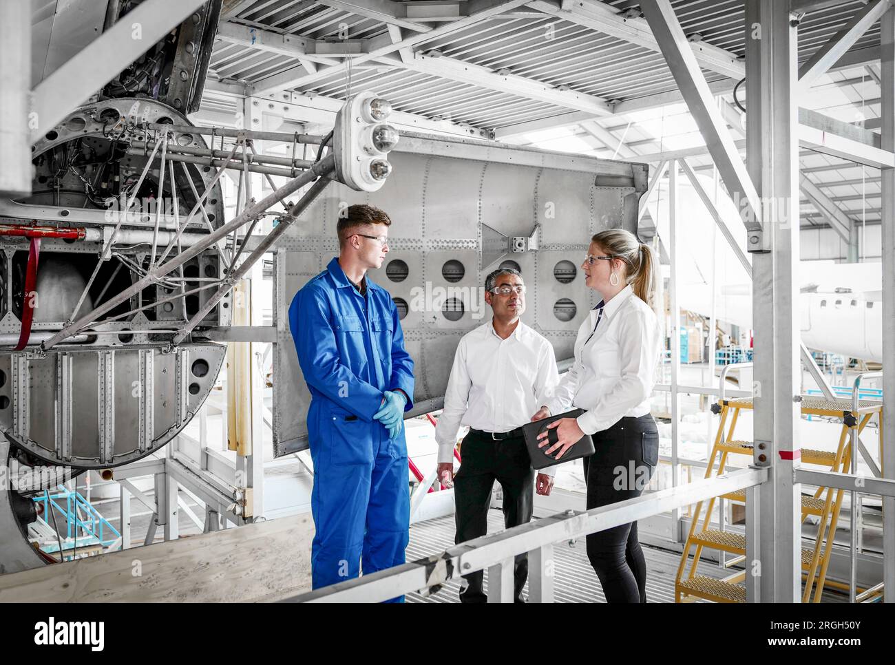 Workers with digital tablet in airplane hangar Stock Photo