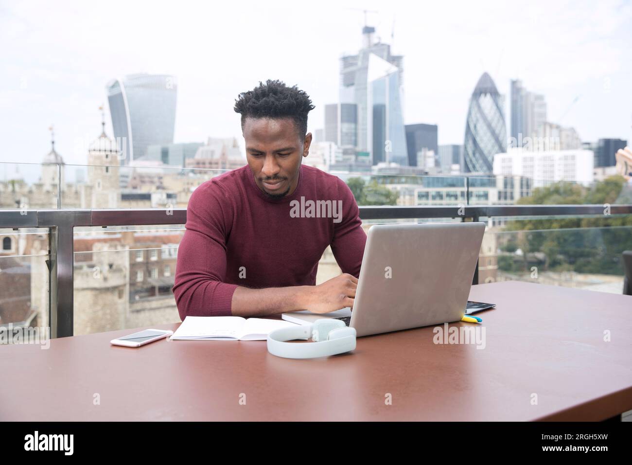 Young man using laptop on balcony Stock Photo