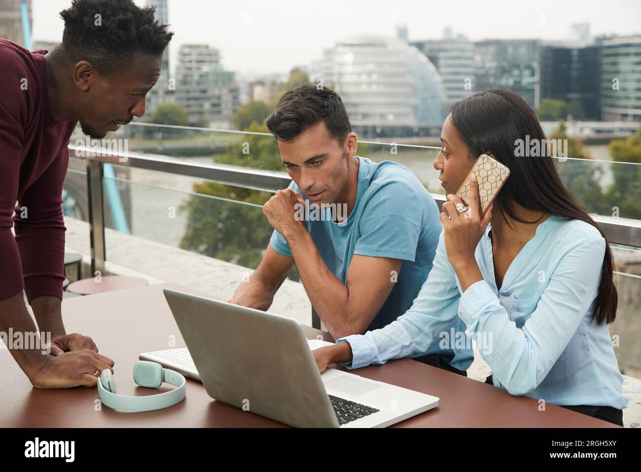 Colleagues using laptop and smart phone on balcony Stock Photo