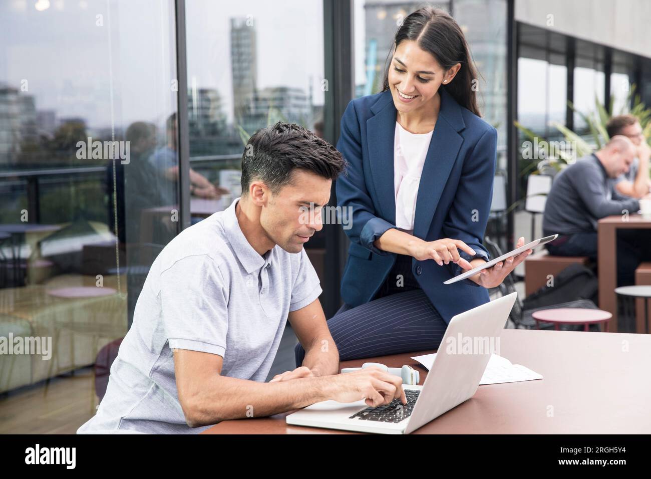 Colleagues using laptop and digital tablet on balcony Stock Photo