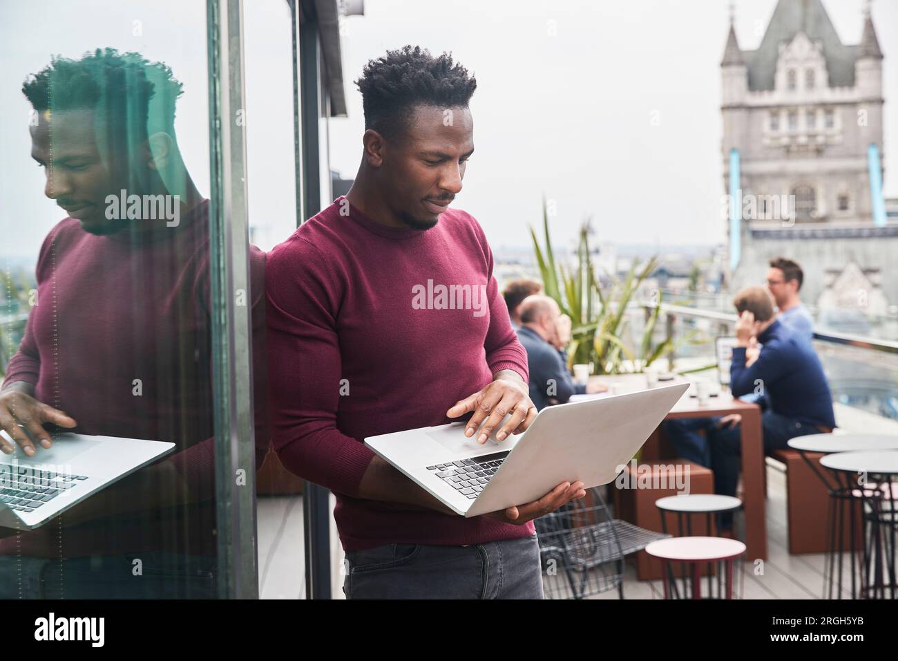 Young man using laptop on balcony Stock Photo