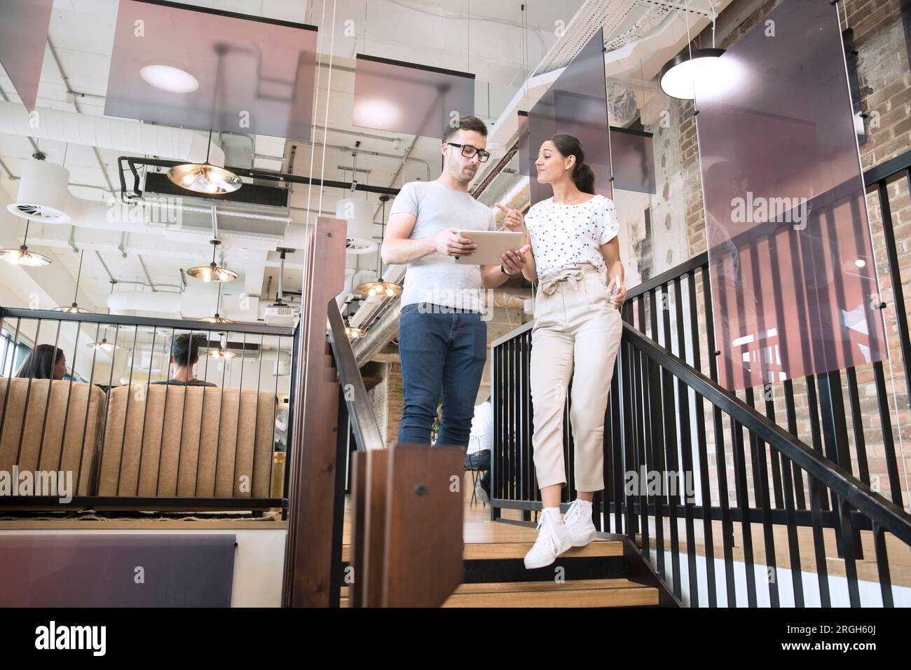 Colleagues using digital tablet on staircase Stock Photo