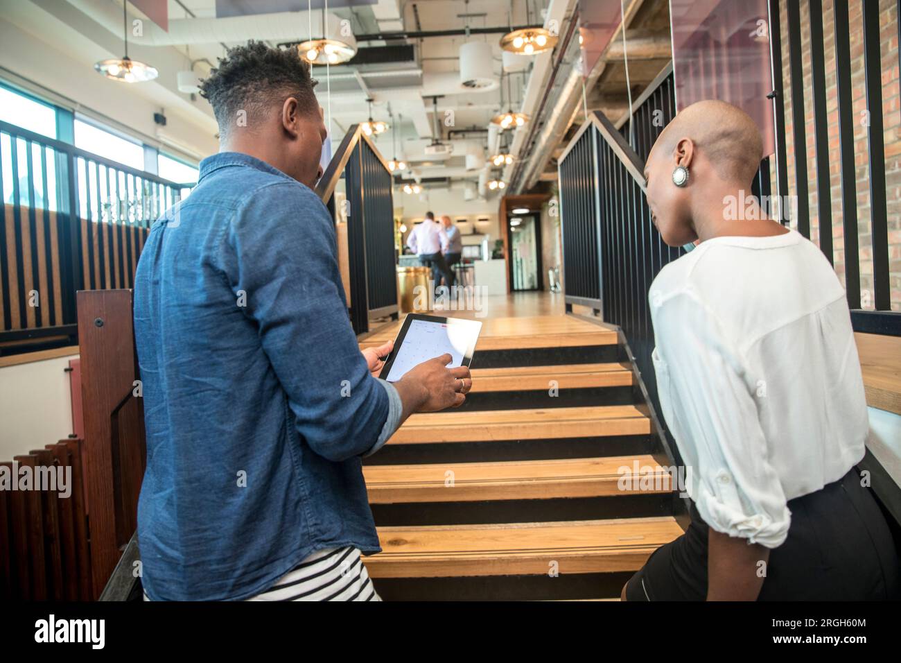 Colleagues using digital tablet on staircase Stock Photo