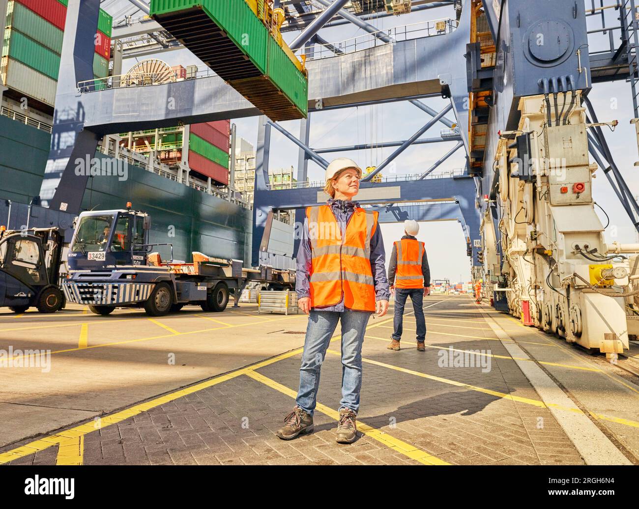 Dock worker in reflective vest beneath crane Stock Photo