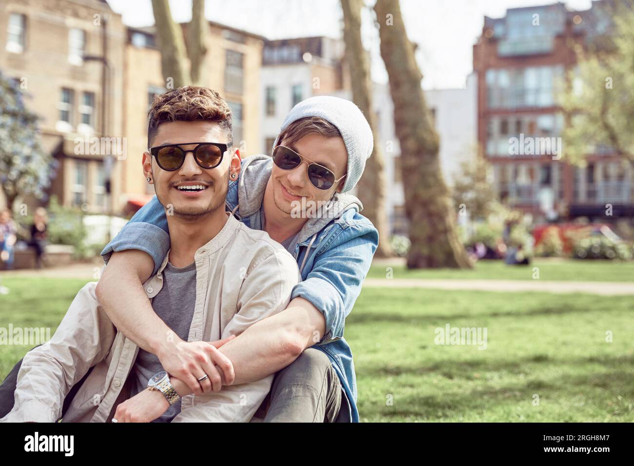 Gay teenage couple sitting together in park Stock Photo