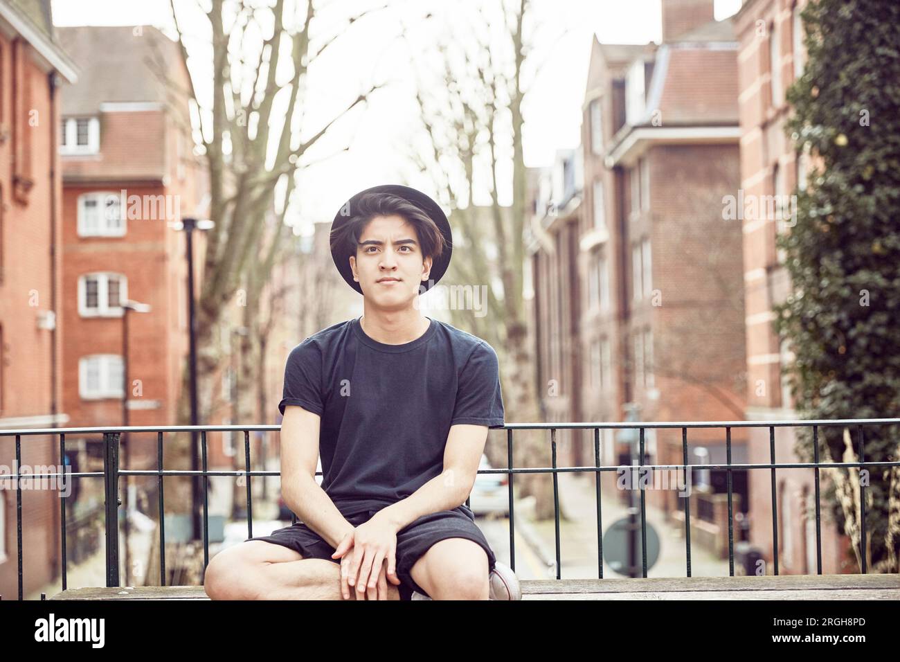 Teenage boy sitting on park bench Stock Photo - Alamy