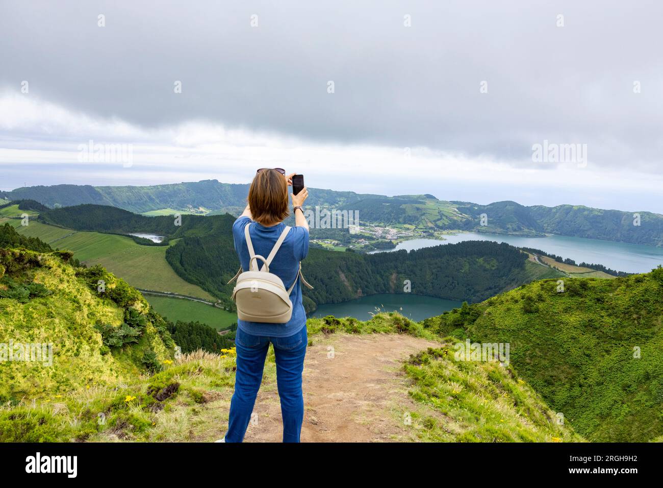 Young woman taking picture of the  beautiful landscape of the Twin Lakes in Sete Cidades in the island of Sao Miguel, Azores, Portugal Stock Photo