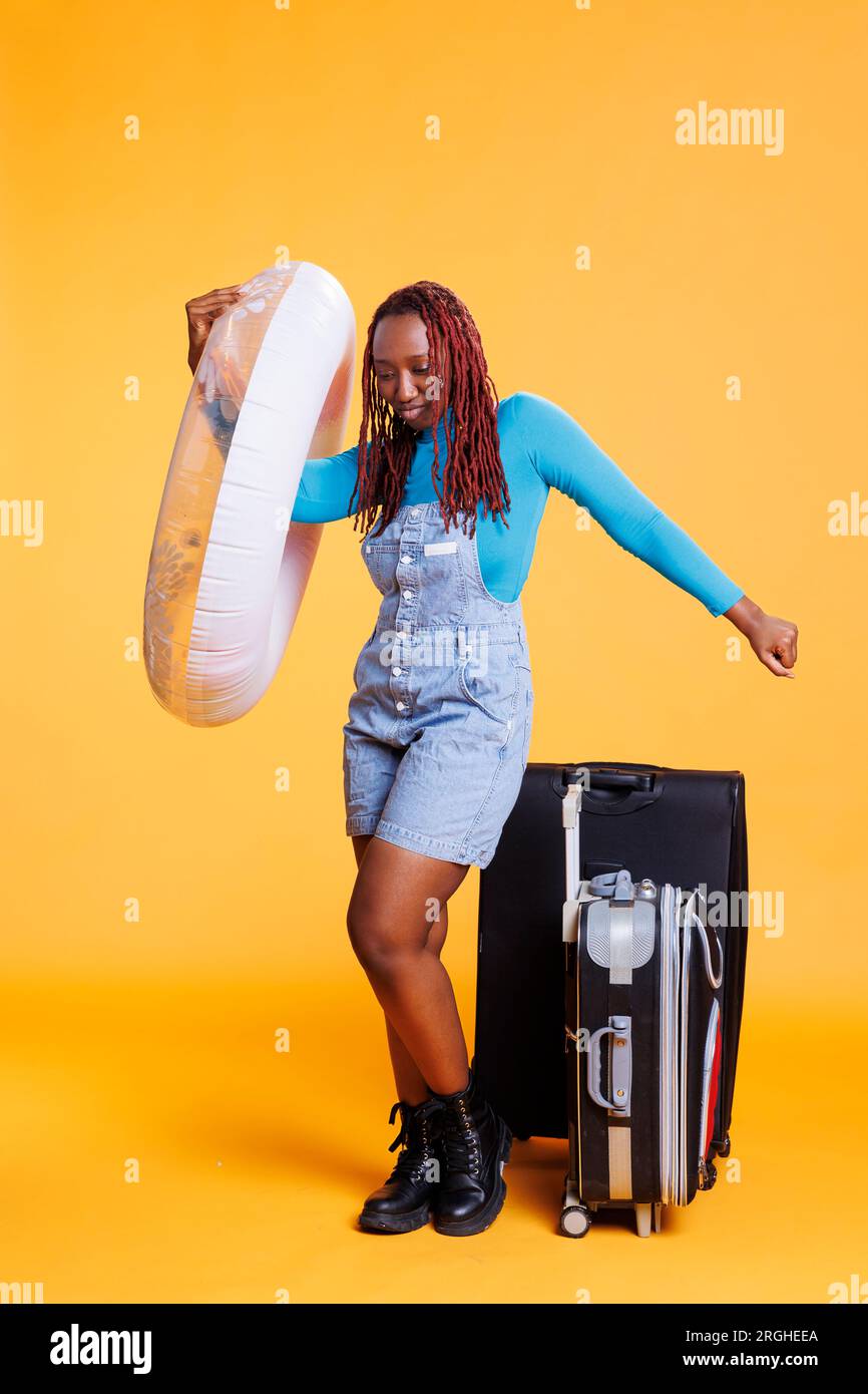 Young tourist with inflatable and bags, carrying ring float and luggage