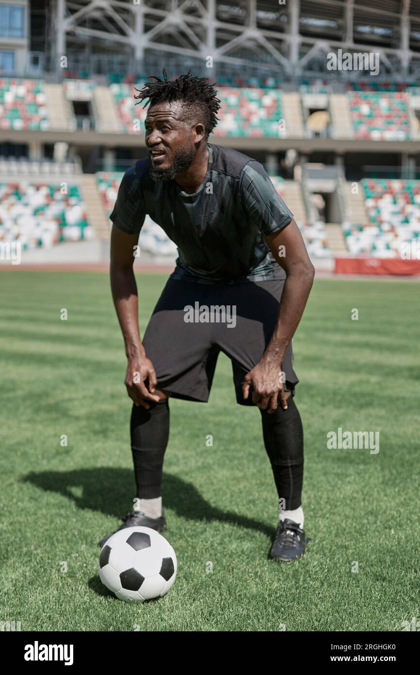 Confident young african american soccer player kicking ball in stadium ...