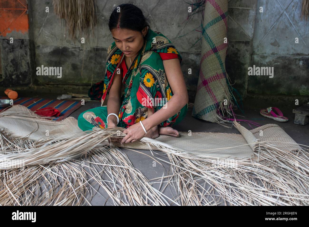 A woman weaves traditional shitol pati (cool mat) at her home in Hailakathi village of Jhalakathi’s Rajapur upazila. Jhalakathi, Bangladesh Stock Photo