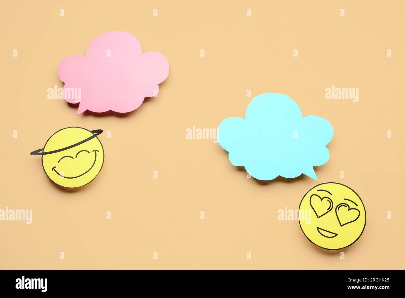 Paper faces with blank speech bubbles on beige background Stock Photo