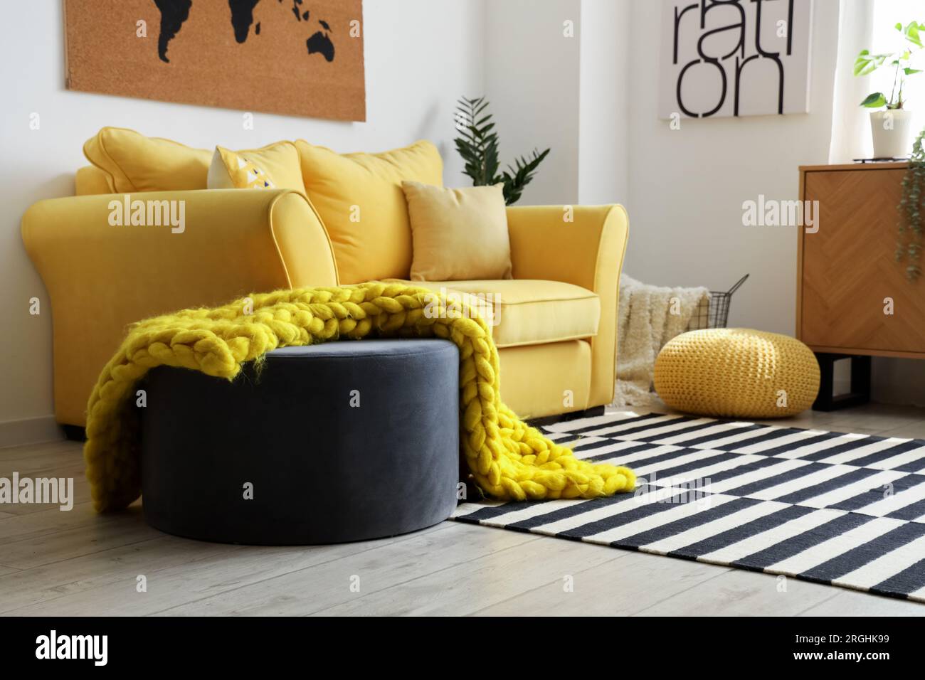Interior of stylish living room with cozy yellow sofa and soft knitted ...