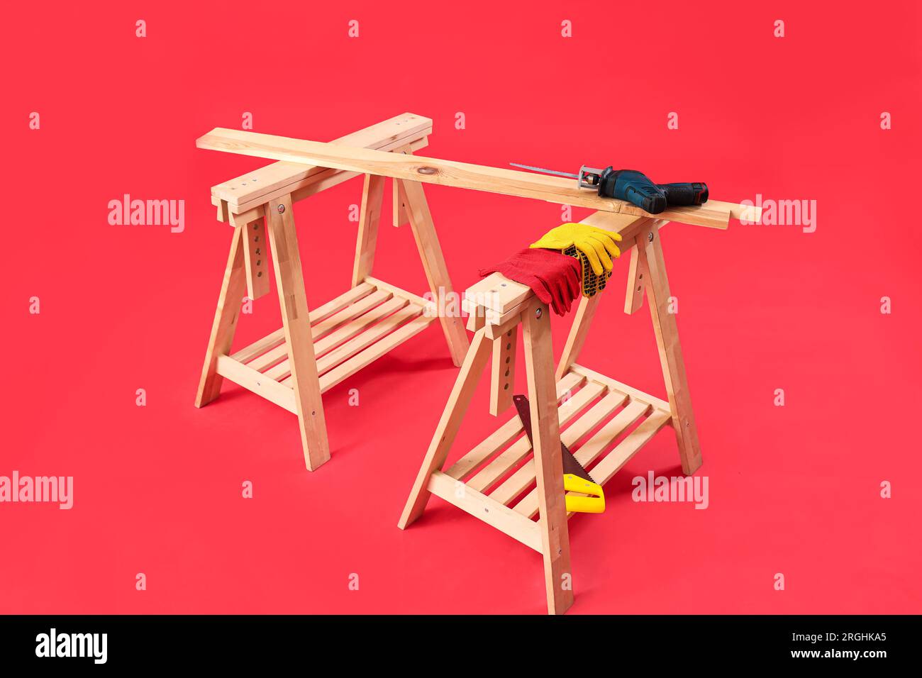 Wooden table with builder's tools on red background Stock Photo