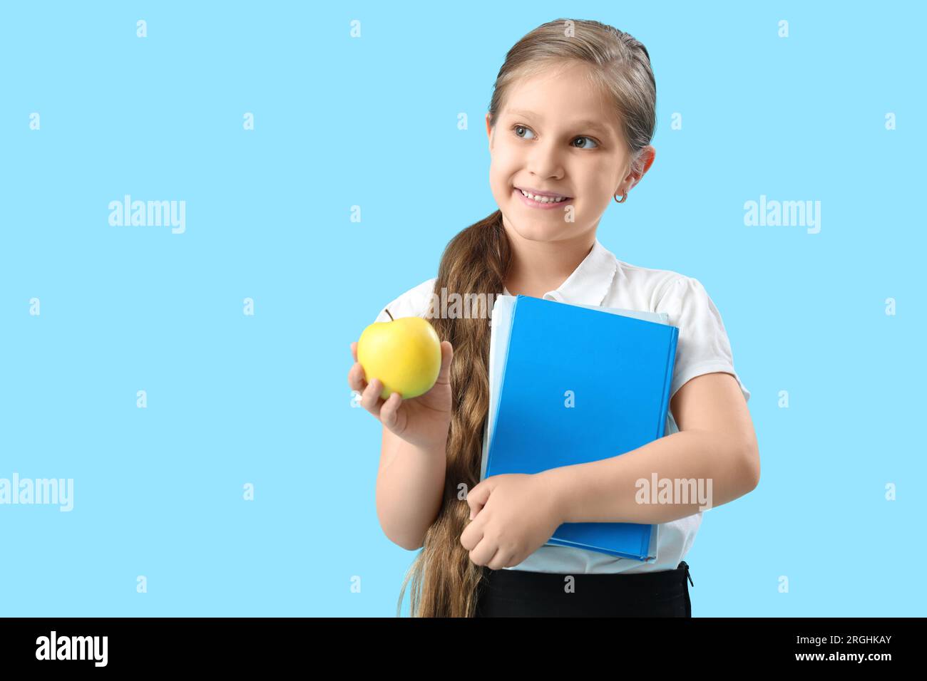 Little schoolgirl with book and apple on light blue background Stock ...