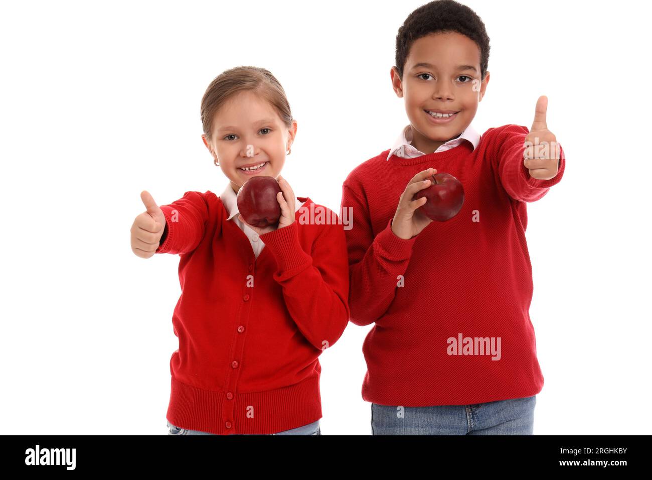 Little students with apples showing thumb-up on white background Stock Photo