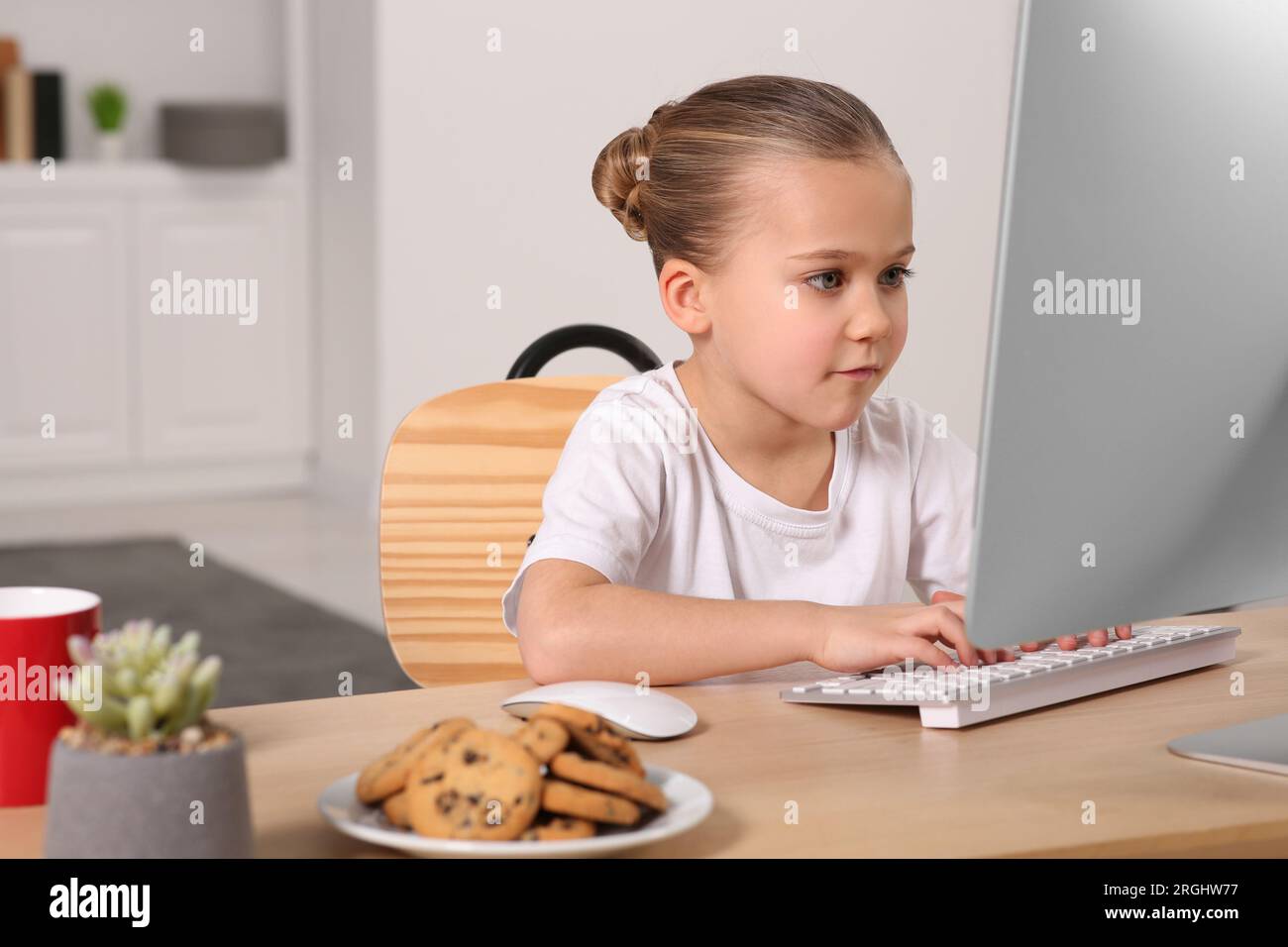 Little girl using computer at table in room. Internet addiction Stock ...