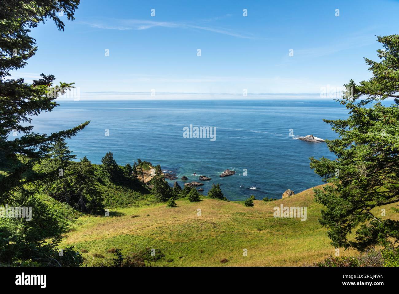 Beautiful blue Pacific Ocean and green cliffside foothills and trees, Oregon Coast, Pacific Northwest Stock Photo