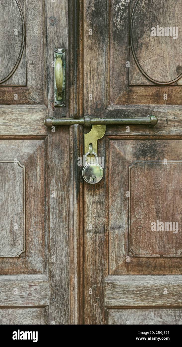 closeup of an old fashioned sliding metal handle and bolt with lock on a classic vintage wooden door Stock Photo