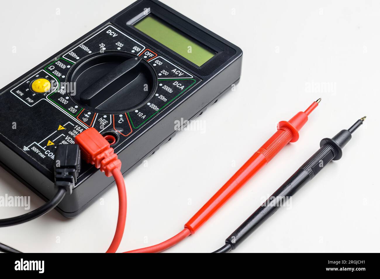 Digital multimeter with test leads on a white table. A multimeter is an ...