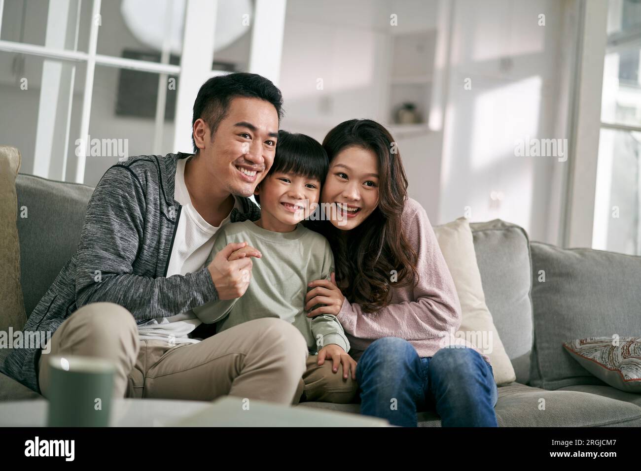 happy young asian family with two children sitting on couch at home enjoying good time together Stock Photo