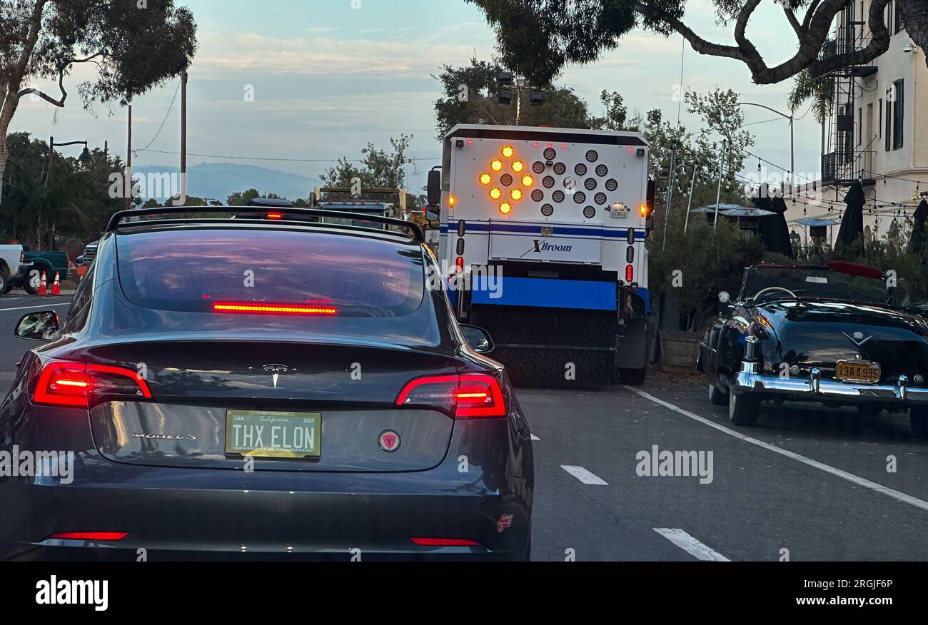 July 30, 2023, Montecito, California, U.S.A: THX Elon license Plate on a Model 3 Tesla driving on Coast Village Road in the luxurious enclave of Montecito, California, home to royalty, movie stars, and business mogals. A classic convertible parked on the side of the road serves as contrast to the Tesla. (Credit Image: © Amy Katz/ZUMA Press Wire) EDITORIAL USAGE ONLY! Not for Commercial USAGE! Stock Photo