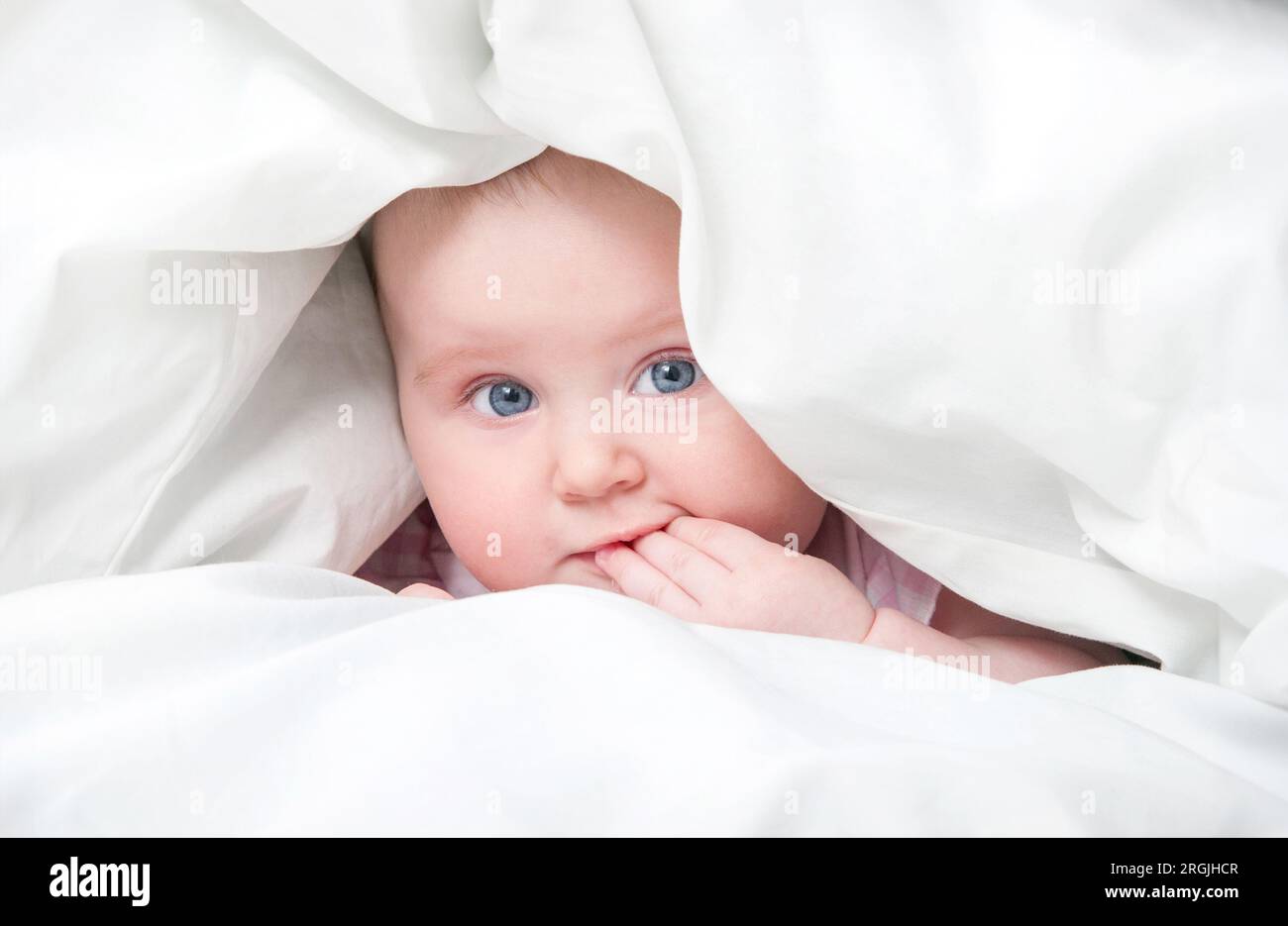 cute baby under a blanket in bed Stock Photo Alamy