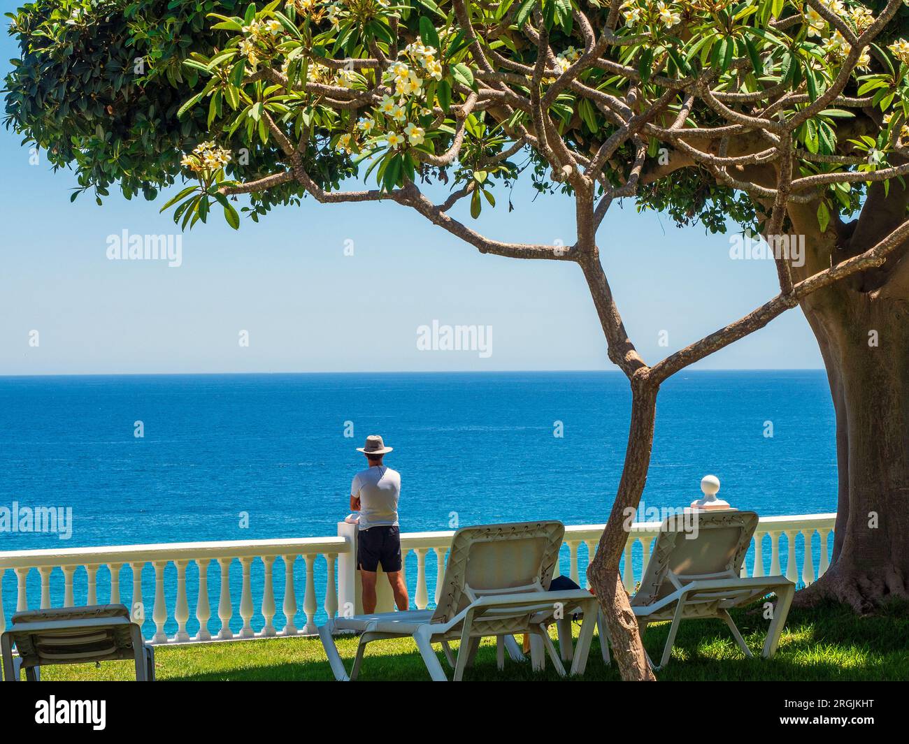 Tourist with hat enjoying the landscape of Nerja from an elevated garden. Stock Photo