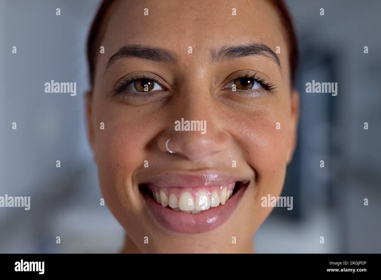 Portrait of happy biracial female doctor with nose piercing in corridor
