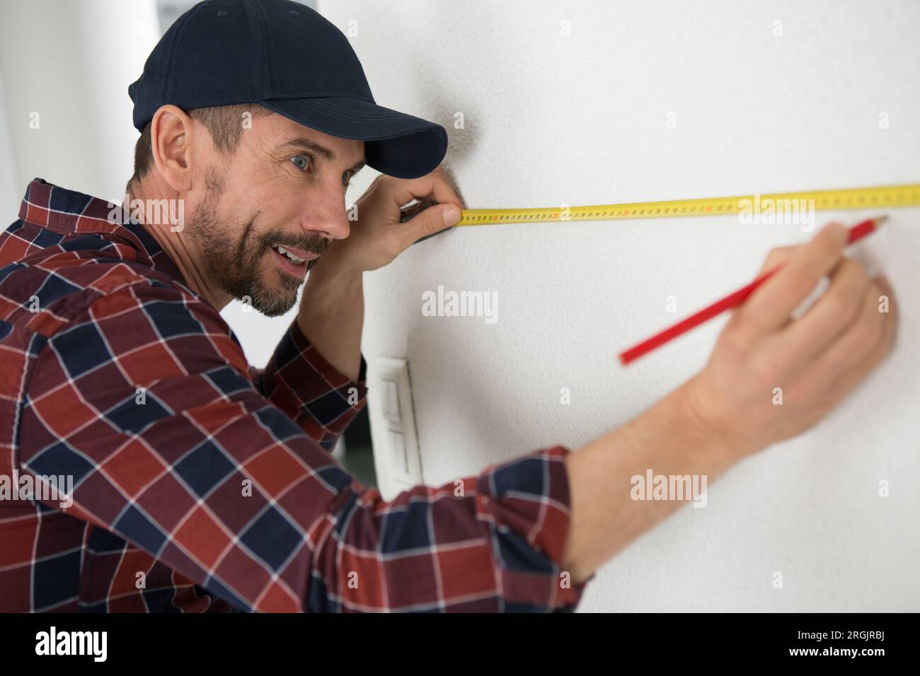 man measures a wall with a ruler Stock Photo