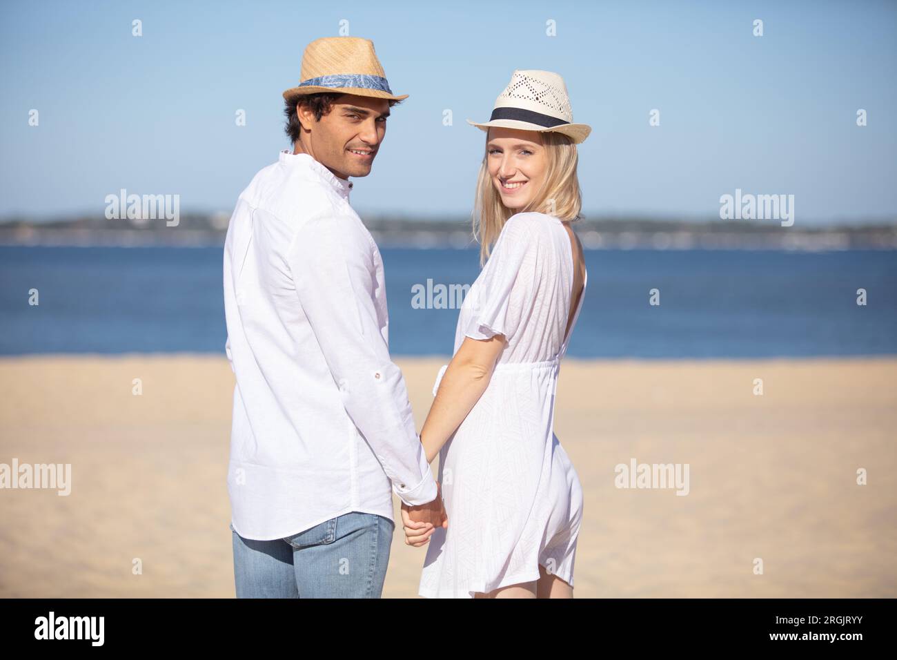 happy young couple holding hands and laughing on the beach Stock Photo