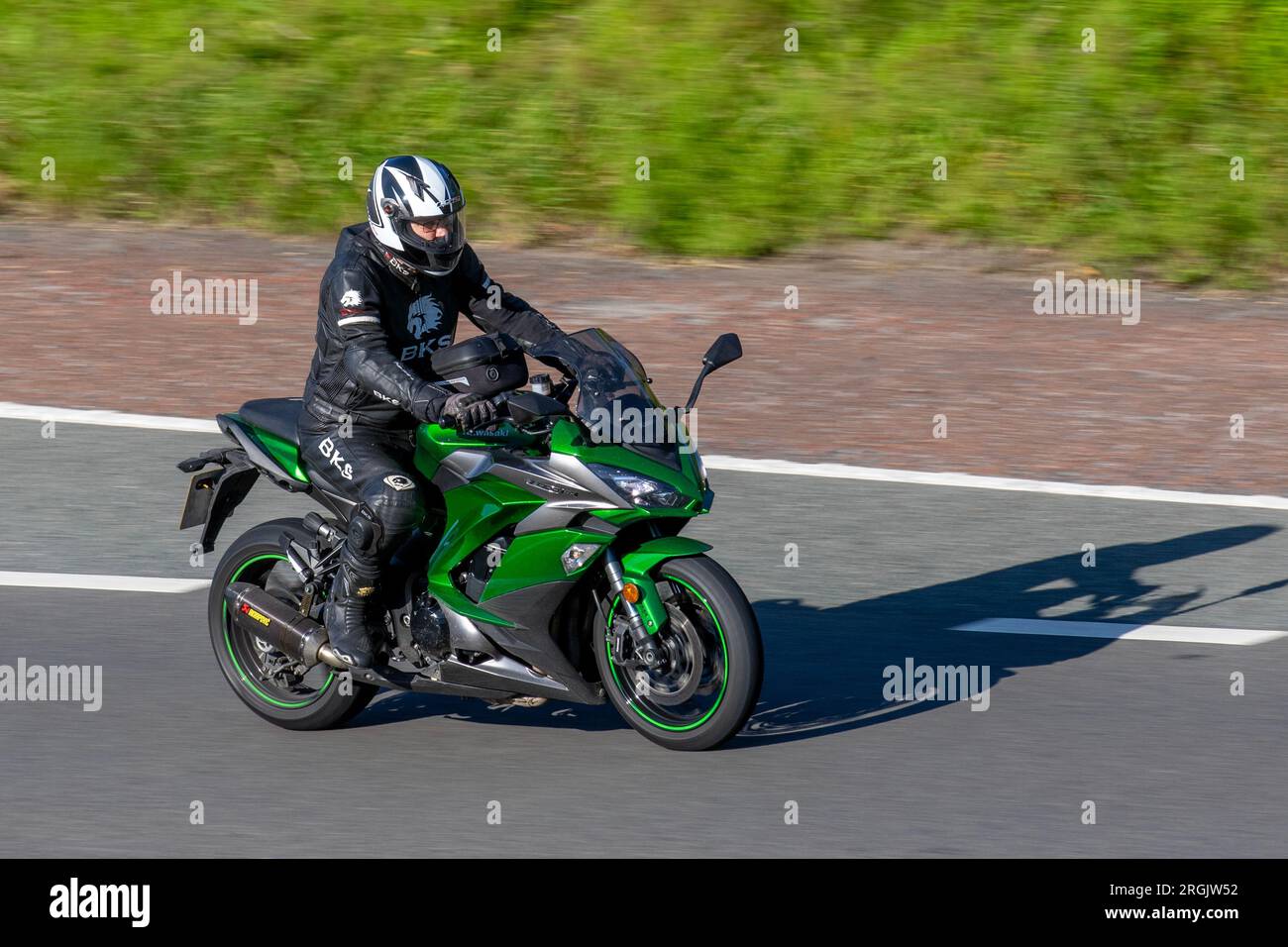 Green Kawasaki Z1000 SX travelling at speed on the M6 motorway in Greater Manchester, UK Stock Photo