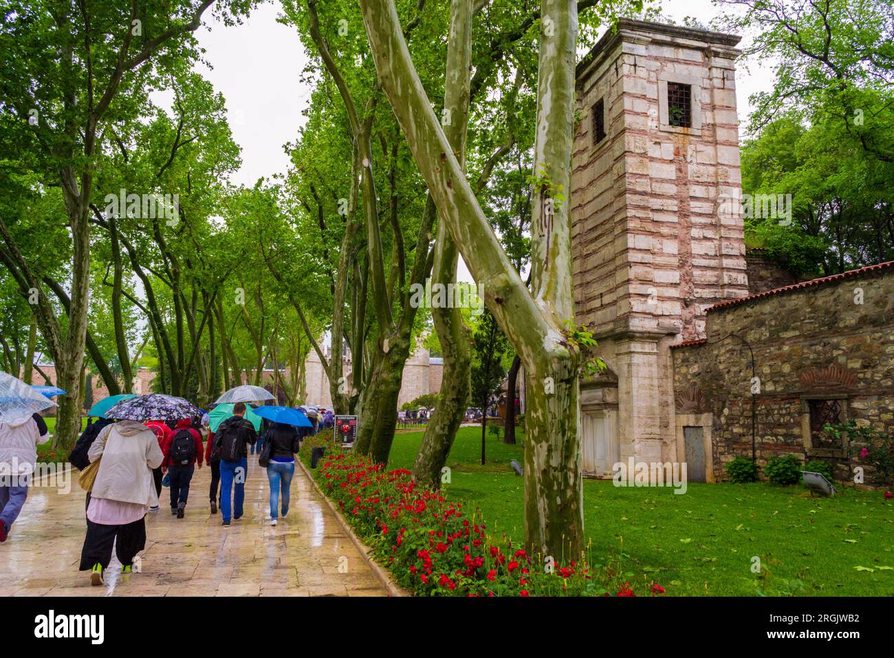 Tourists walking in the rain on a walkway leading to Topkapi Sarayi Palace-Unesco World Heritage SITE .Topkapi is a large museum and library. Stock Photo