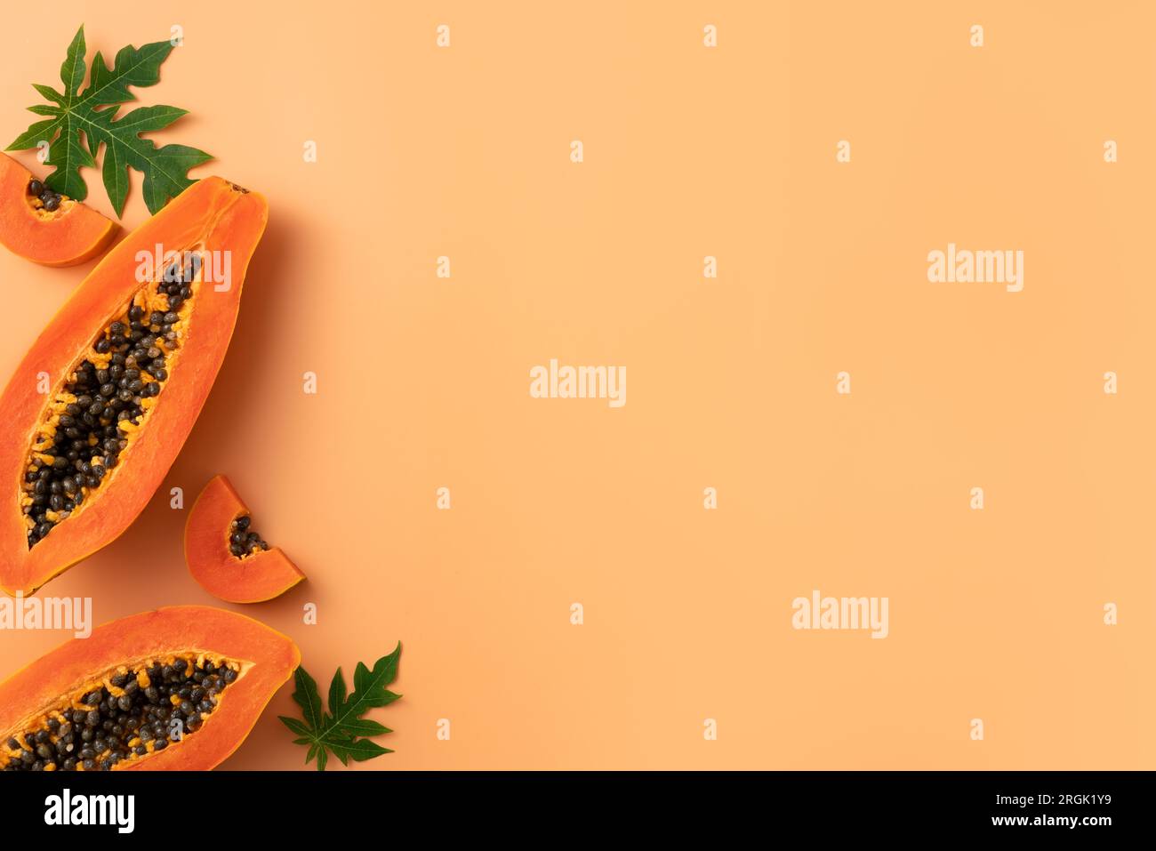 Cut Papaya over orange table background for tropical fruit design concept, top view copy space. Stock Photo