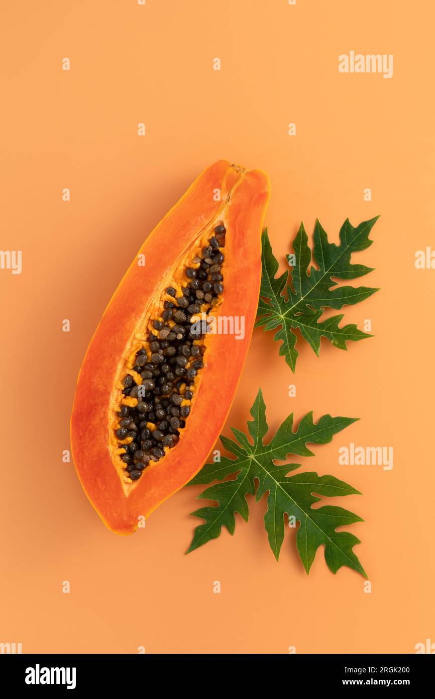 Cut Papaya over orange table background for tropical fruit design concept, top view copy space. Stock Photo