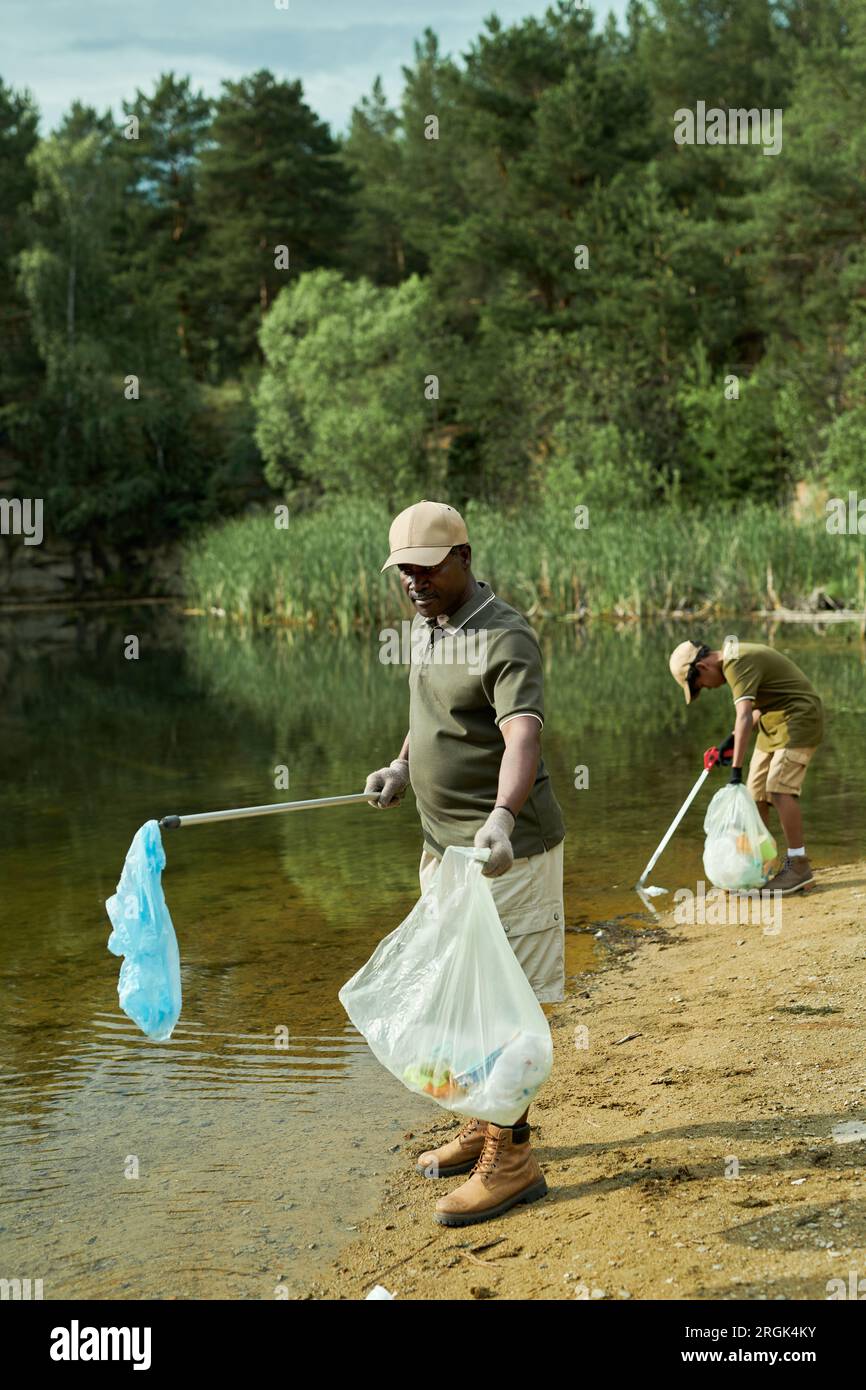 Vertical image of volunteers cleaning the lake from garbage outdoors Stock Photo
