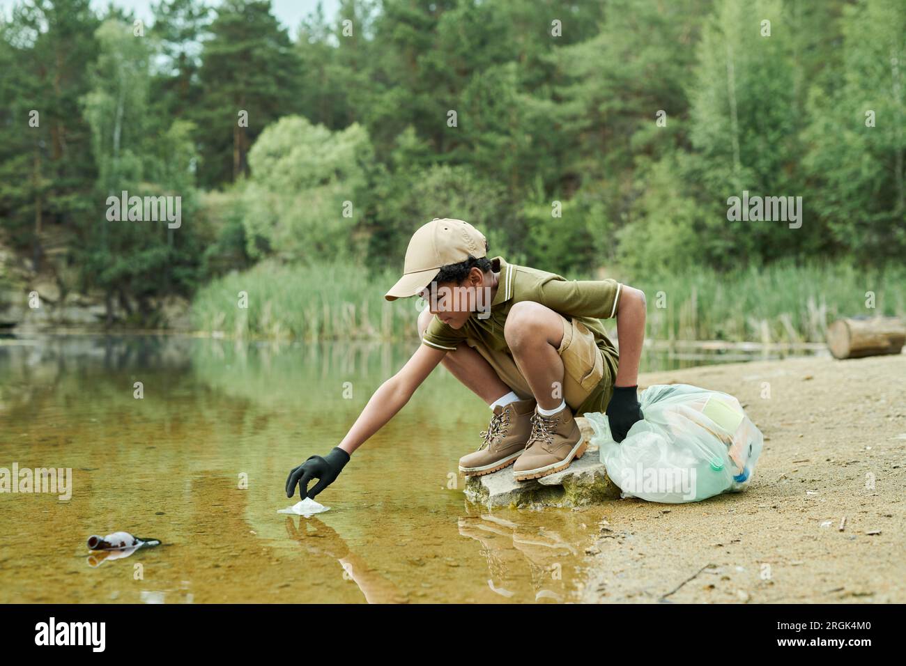 African American boy cleaning the water from garbage outdoors Stock Photo