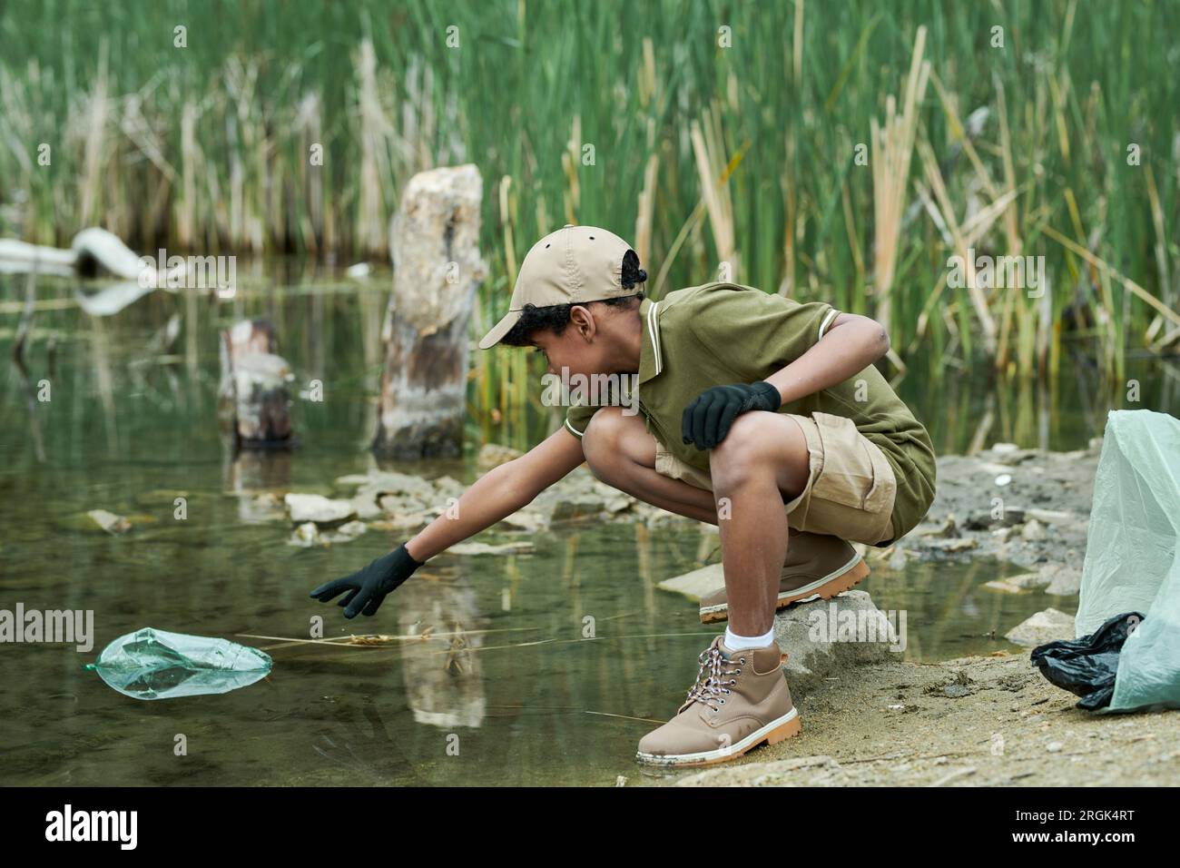 African American activist cleaning the water from garbage outdoors Stock Photo