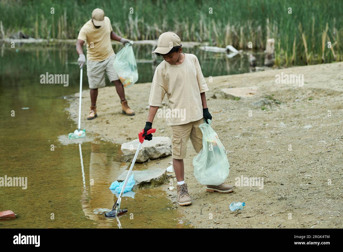 Family cleaning water from garbage together outdoors Stock Photo