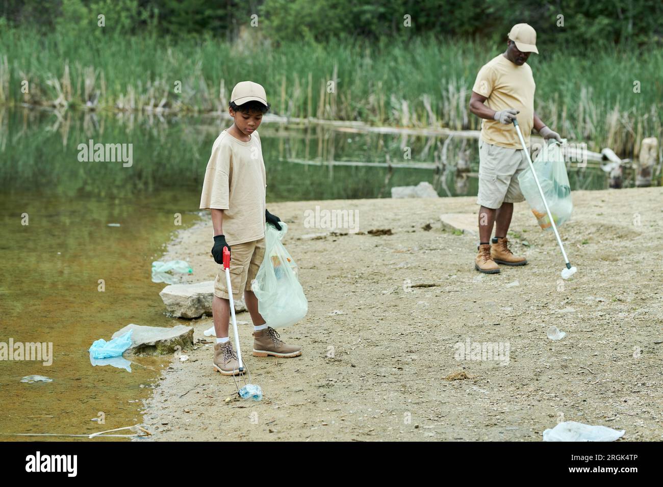 Family of two cleaning the territory of lake together outdoors Stock Photo