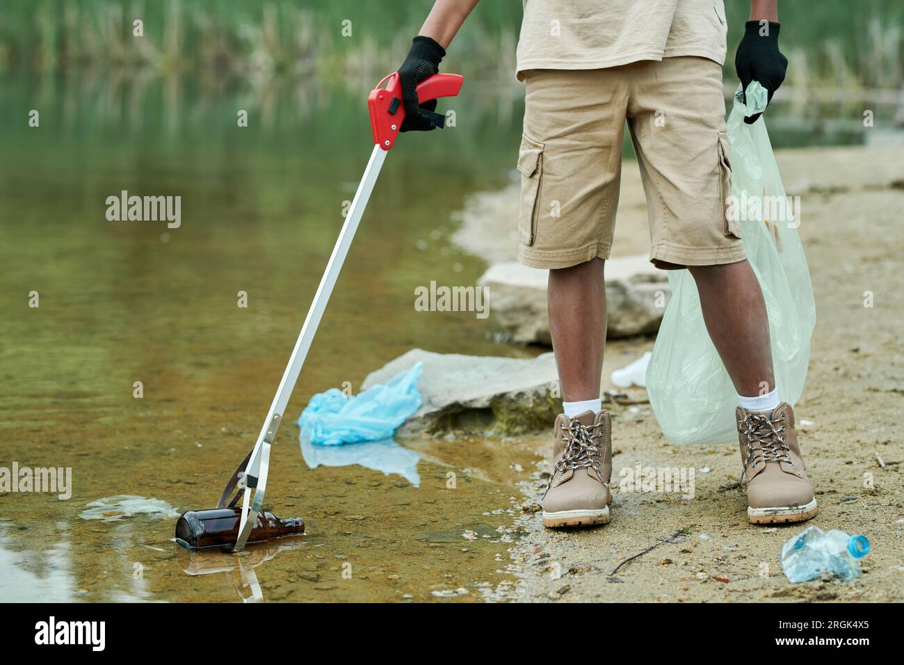 Close-up of child cleaning the water from garbage with special stick Stock Photo